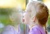 Girl licking her reflection on a window glass