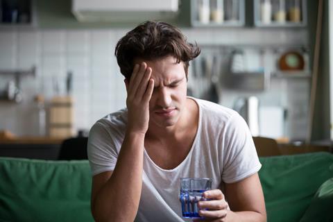 A man with a headache and a glass of water