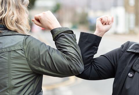 To avoid hand-to-hand contact during the coronavirus pandemic, two people bump elbows as a greeting