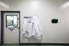 Closed door to laboratory with lab coats hanging from coat rack