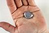 A close-up photo of someone's hand holding a walnut-sized blob of shiny metal that is starting to melt around the edges