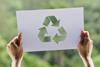 Hands holding sign with recycling symbol on it