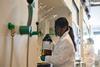 A photograph of a woman wearing PPE handling DCM in a laboratory