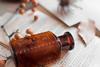 Image of a brown poison bottle lying on a book and notes, surrounded by poison pills