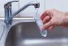 A hand filling a sample tube with water from a domestic tap