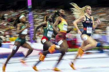 Female track runners competing in a race at a full stadium