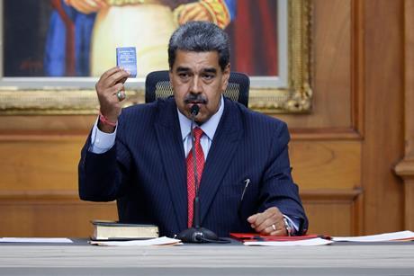 A politician holds up a very small copy of the Venezuelan constitution