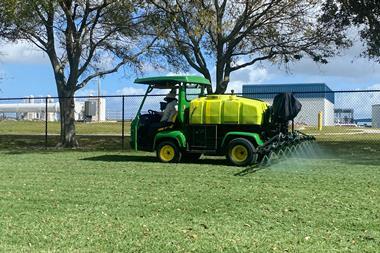 Landscapers using a small spraying vehicle to spray an area of grass